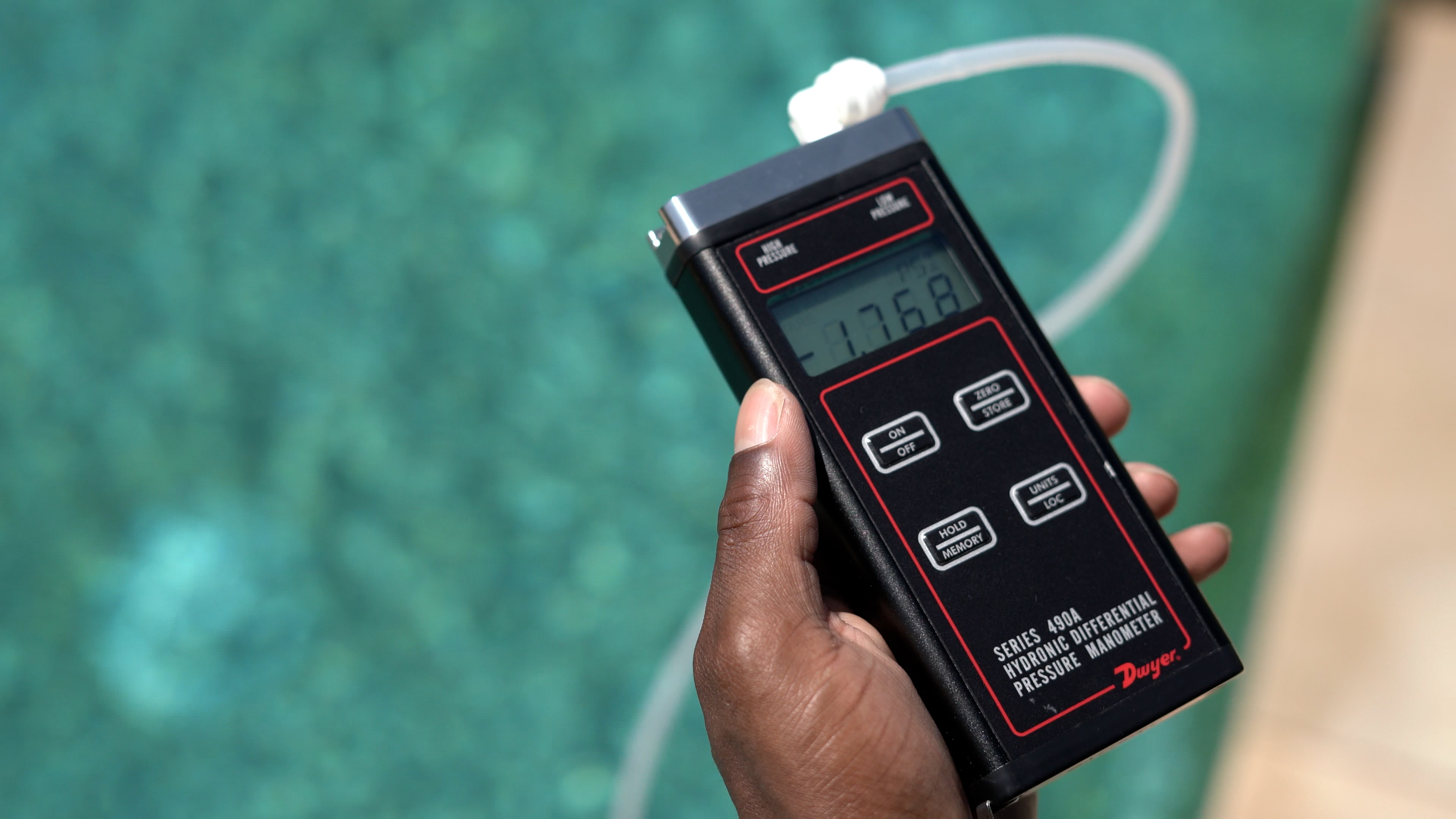 Dolphin Cayman Hand Holding Pressure Meter Near Pool