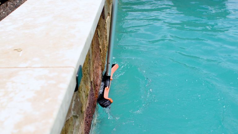 Pool Maintenance Brush Bristles Against Stone Wall Close Up